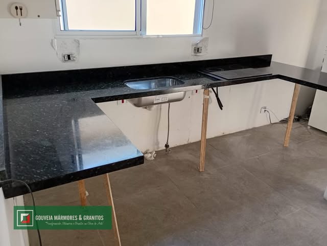 Bancada de granito escuro com cuba inox durante a instalação