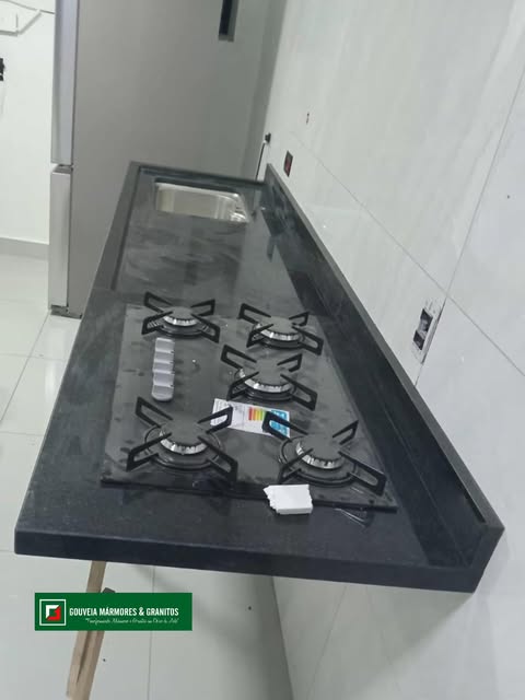 Bancada de granito escuro com cooktop instalada em cozinha