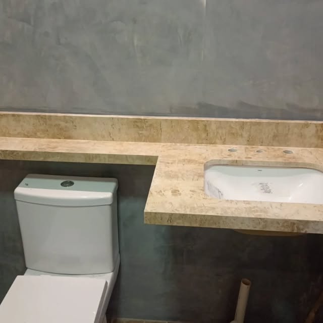 Bancada de banheiro em pedra bege com cuba embutida e rodabancada