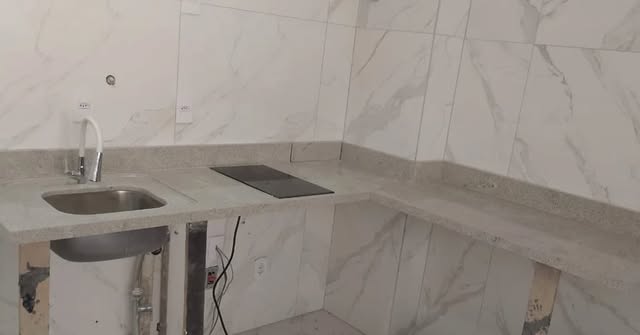 Bancada de cozinha em L em pedra clara com cuba e cooktop